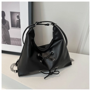 Detail of silver metal eyelets with lace-up decor on a black faux leather tote bag