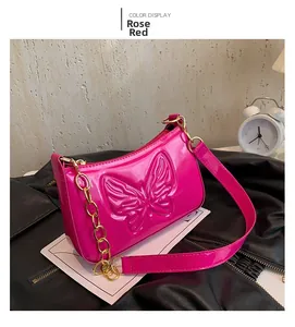 Detail of rose red patent leather shoulder bag featuring 3D butterfly embossing and gold chain
