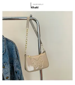 Detail of khaki patent leather baguette bag featuring a large embossed butterfly and chain