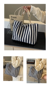 Detail of striped canvas tote bag with leather handles and gold chain decoration