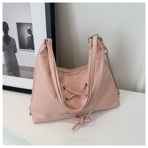 Close-up of pink tote bag featuring a lace-up design with bow detail and silver chain strap