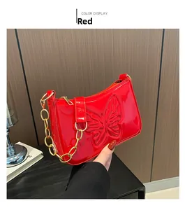 Detail of red glossy patent leather bag with embossed butterfly and gold chain