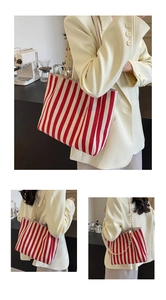 Detail view of a large striped canvas tote bag with gold chain and beige leather straps