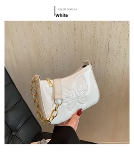 Detail of white glossy patent leather bag with butterfly embossing and gold chain