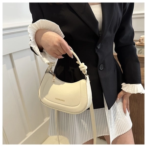 Close-up of cream crescent crossbody bag with knotted handle and fashion text detail