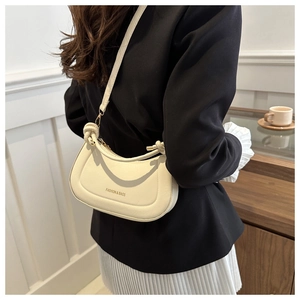 Detail view of the cream crescent moon shoulder bag with gold hardware and logo