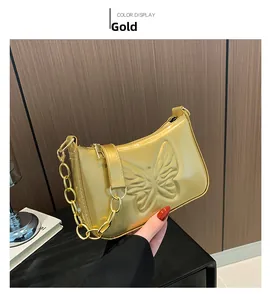 Macro shot of 3D butterfly relief and gold patent leather texture on chic underarm bag