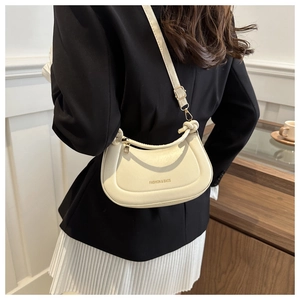 Detail of a creamy white crescent bag showing the adjustable strap and smooth leather texture