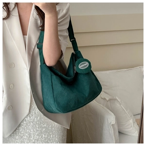 Detail view of dark green corduroy bag showing fine rib texture and hanging coin pouch