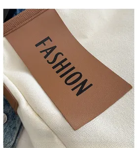 Dettaglio ravvicinato della tela con toppa in pelle marrone e scritta FASHION stampata