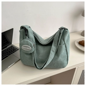 Détail du sac fourre-tout en velours vert avec texture rayée et petite fente pour pièces