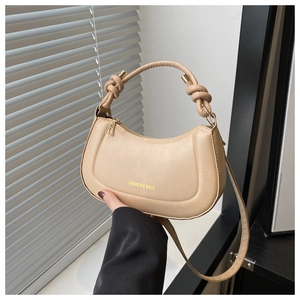 Detail of knot handle and golden metal ring on this beige crescent PU handbag