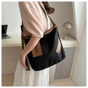 Dettaglio di una grande borsa tote in tela con etichetta FASHION in pelle marrone e tracolla