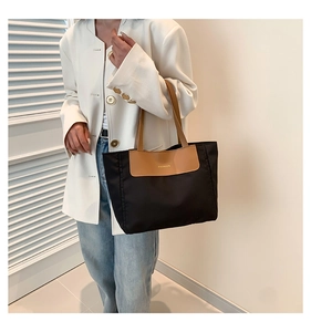 Close-up of contrast color nylon tote bag with leather handles shown on a model