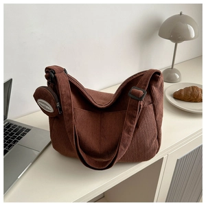 Détail du sac hobo en velours côtelé marron foncé avec bandoulière et mini pochette ronde