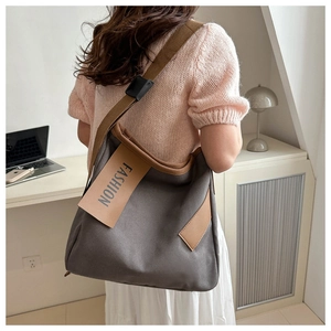 Dettaglio della borsa tote in tela grigio scuro con spalline marroni e etichetta FASHION