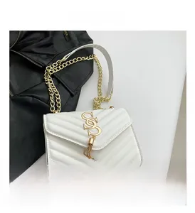 Detailed shot of white V-quilted faux leather bag with gold chain and metal tassel