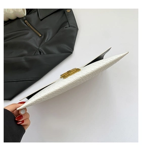 Dettaglio della pochette in pelle intrecciata bianca con chiusura in metallo dorato e trama