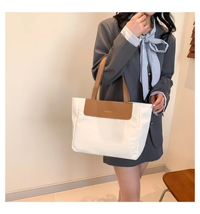 Close-up of the stylish color-block tote bag featuring brown leather straps and fashion logo