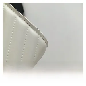 Macro detail of white leather crossbody bag featuring vertical stitching and soft texture