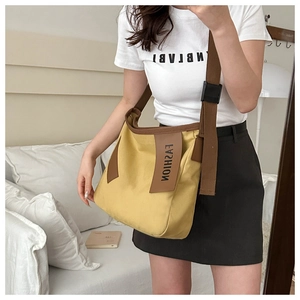 Grande borsa tote in tela gialla con tracolla marrone e dettaglio etichetta moda
