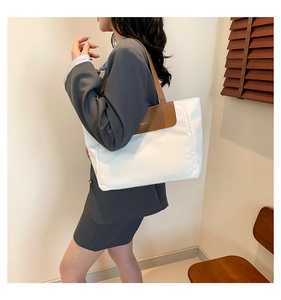 Detail shot of a large contrast color tote bag with white fabric and brown leather straps