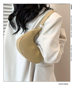 Detailed view of beige crescent saddle bag with gold zipper shown on shoulder