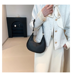 Chic black crescent underarm bag in lychee leather styled with a white tweed jacket