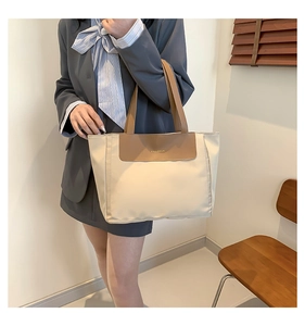 Woman carrying large cream nylon tote bag with brown handles in minimalist room