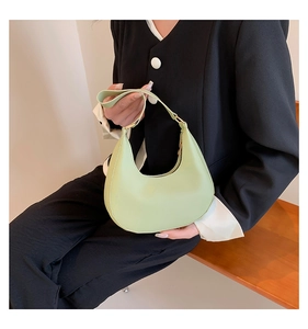 Detail shot of light green crescent saddle bag showing smooth leather and metal zipper