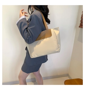 Detail view of stylish color-block tote bag featuring canvas fabric and leather straps