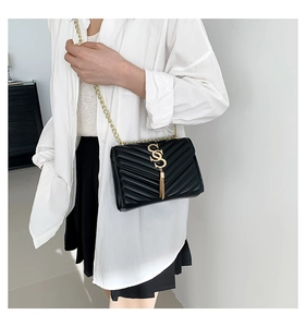 Close-up of black quilted shoulder bag with gold V-pattern and metallic S logo