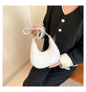 Detail of white PU leather crescent shoulder bag featuring gold hardware and zipper