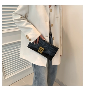 Dettaglio della pochette a busta in pelle nera con fibbia geometrica in metallo oro