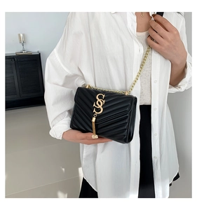 Detail of black V-quilted leather shoulder bag with gold chain strap and metal clasp