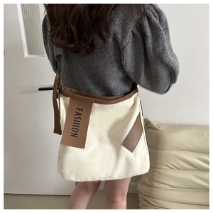 Dettaglio della borsa tote in tela con etichetta in pelle fashion e tracolla marrone
