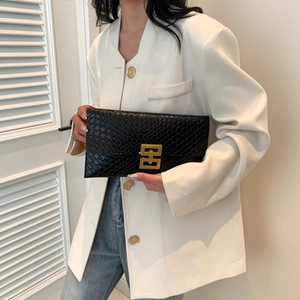 Dettaglio pochette nera con motivo a serpente e chiusura geometrica in metallo dorato