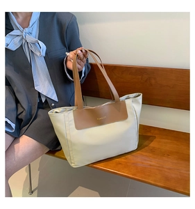 Detailed view of beige nylon tote bag with brown leather handles and fashion logo text
