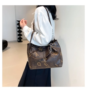 Side view of large dark brown tote bag with gold lettering and silver chain detail