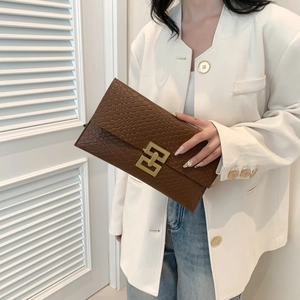 Pochette marrone con trama intrecciata e fibbia in metallo dorato su un blazer bianco