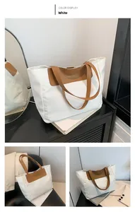 Detailed view of large white tote bag with brown leather handles and golden fashion text
