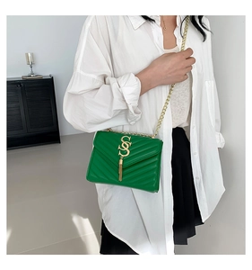 Detail of green quilted crossbody bag with golden tassel S-logo and metal chain strap