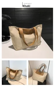 Detail view of khaki nylon tote bag with brown leather handles and fashion logo print