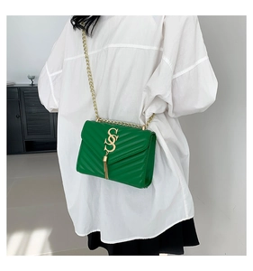 Detail of green chevron quilted crossbody bag with gold chain and tassel accent