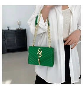 Detail of green quilted chain bag with V-shaped stitching and golden tassel logo