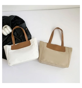 Detail of minimalist tote bags with leather handles and gold fashion lettering logo
