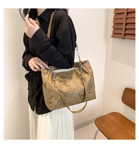 Detail of beige tote bag with letter prints and silver metal chain shoulder straps