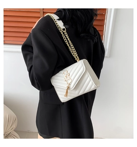 White crossbody bag featuring V-quilted stitching and chain strap on female model