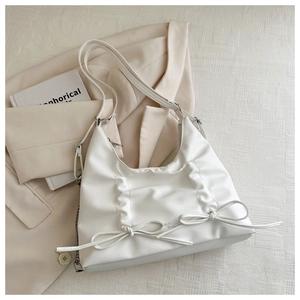 Dettaglio della borsa a mezzaluna in pelle PU bianco crema con fiocchi e catena metallica