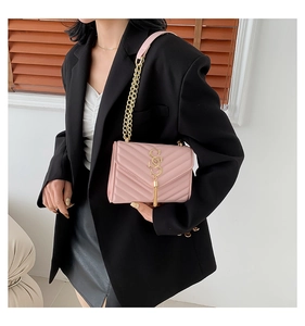 Detail of pink quilted square crossbody bag with metallic chain strap and fringe tassel